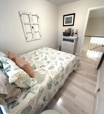 a bedroom with a bed with a floral comforter at coastal and cozy beach stay, pet friendly in Milford