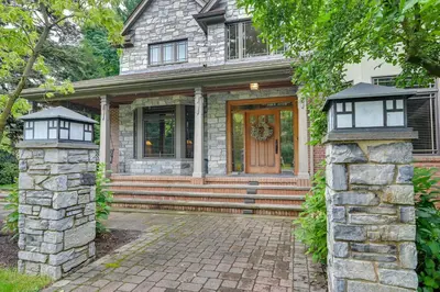 a house with a stone pillar and a door at Hot Tub, Gym, Game Room! Luxe Estate in Longmeadow in Longmeadow