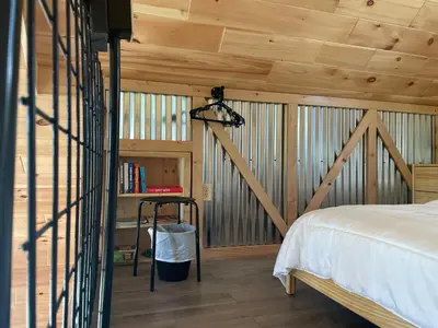 a bedroom with wooden walls and a bed and a staircase at Countryside Views in Norwich