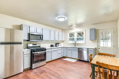 a kitchen with white cabinets and a wooden table with a tableablish at 1 Mi to Dtwn Saratoga Springs Cozy Duplex Apt! in Saratoga Springs