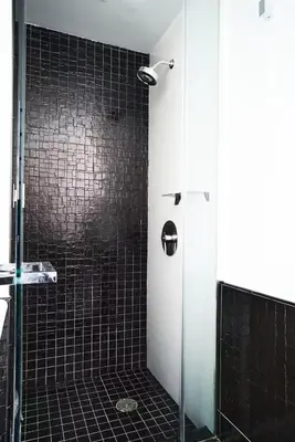 a bathroom with a shower with a black tile wall at W residence in New York