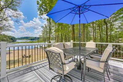 a table and chairs on a deck with a blue umbrella at Boat, Fish and Unwind Waterfront Gem in Pocono Mtns in Lake Ariel