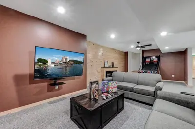 a living room with a couch and a flat screen tv at Tree Haven- fenced yard, hot tub, fire pit in Hawley