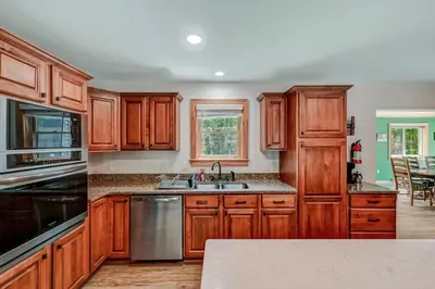 a kitchen with wooden cabinets and stainless steel appliances at Tree Haven- fenced yard, hot tub, fire pit in Hawley