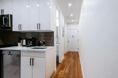 a kitchen with white cabinets and a wooden floor at 3BD 2BA in Upper West Side Manhattan! 5 Star Location in New York