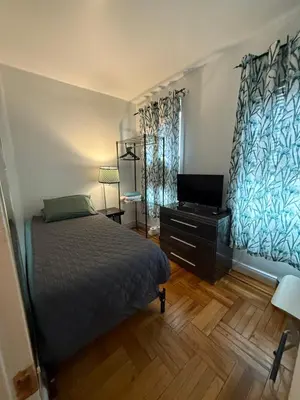 a bedroom with a bed and a flat screen tv at Bronx City Stay Private Room Near Manhattan in Kings Bridge Heights