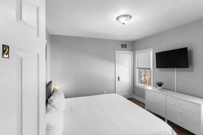 a white bedroom with a bed and a flat screen tv at Cozy Bedroom next to SCSU in New Haven
