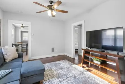 a living room with a blue couch and a flat screen tv at Cozy Bedroom next to SCSU in New Haven