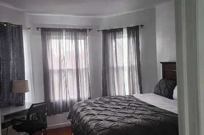 a bedroom with a bed and a desk and windows at Massive 5 bedroom Close to NYC in Newark