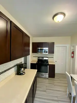 a kitchen with wooden cabinets and a stove top oven at Tropical Oasis - Room 1 in Irvington
