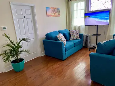 a living room with a blue couch and a tv at Tropical Oasis - Room 1 in Irvington
