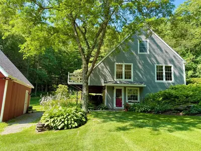 a gray house with a tree in the yard at Beautiful House in the Woods, Huge Yard, Hot Tub in Great Barrington