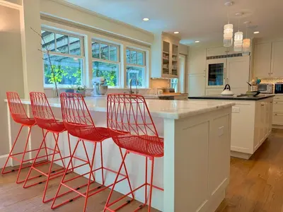 a kitchen with four red bar stools at a counter at Beautiful House in the Woods, Huge Yard, Hot Tub in Great Barrington