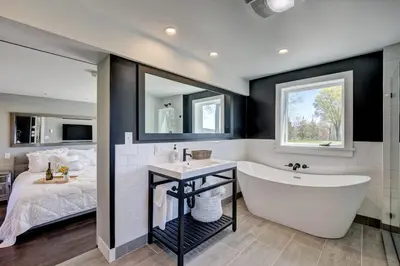 a bathroom with a large tub and a bed at Longpond Farm House and Loft in Salisbury