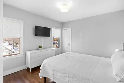 a white bedroom with a bed and a flat screen tv at Quiet & Cozy Room by SCSU in New Haven