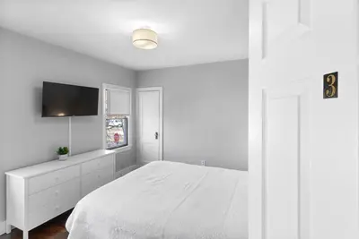 a white bedroom with a bed and a flat screen tv at Quiet & Cozy Room by SCSU in New Haven