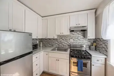 a kitchen with white cabinets and a stove top oven at Neighborhood Apt-walk to Train-McLean Ave, 30mins to NYC in Yonkers