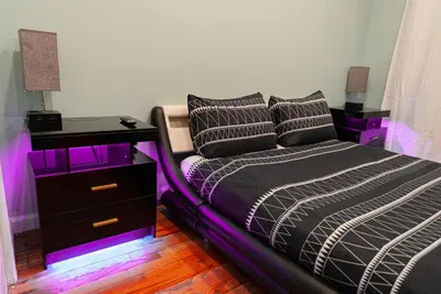a bedroom with a bed and a nightstand with purple lights at Hells Kitchen Hideaway in New York