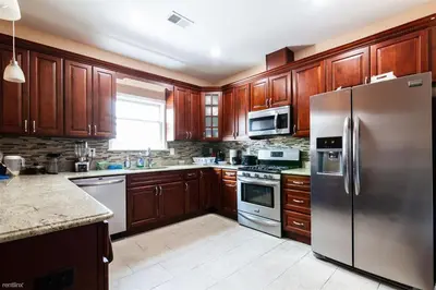 a kitchen with wooden cabinets and a stainless steel refrigerator at Quiet apt only 15 mins from Midtown NYC in Jersey City