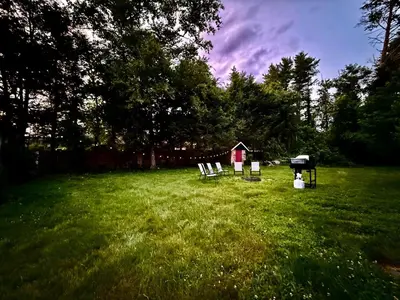 a yard with two chairs and a grill in the grass at Country Comfort Cabin Delaware River Islands in Montague