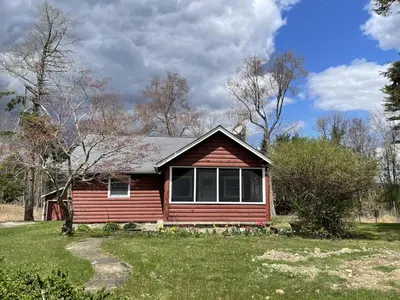 a small red house in a grassy yard at Country Comfort Cabin Delaware River Islands in Montague