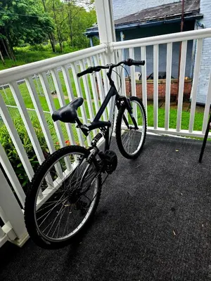a bike parked on a porch next to a fence at NEW 