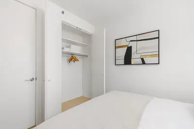 a white bedroom with a bed and a picture on the wall at Blueground Williamsburg view nr East River NYC-1958 in Brooklyn