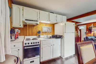 a kitchen with white cabinets and a stove and refrigerator at Ski Haus Retreat - Unit A in Dover