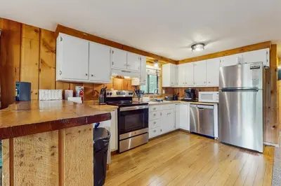 a kitchen with white cabinets and stainless steel appliances at Ski Haus Retreat - Unit B in Dover