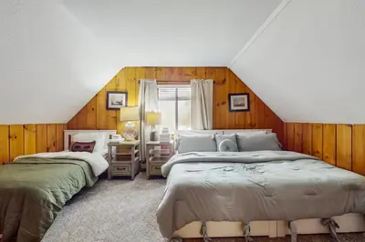 two beds in a room with wooden walls at Ski Haus Retreat - Unit B in Dover