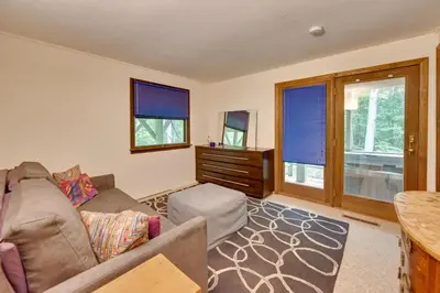 a living room with a couch and a table and windows at Tolland Lake Escape Kayaks Deck and Nature Trails in Sandisfield