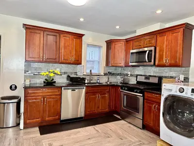 a kitchen with wooden cabinets and a washer and dryer at BP STAYS - Hotel-Style, No Host, Professionally Managed ID260 in Jersey City