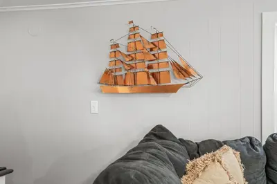 a wooden ship hanging on a wall next to a couch at Lake Me Home in East Hampton