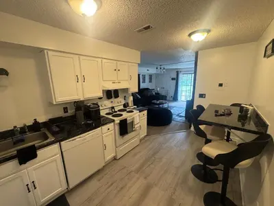 a kitchen with white cabinets and a table and a counter at Elegance Escape