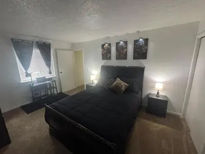a bedroom with a black bed and two windows at Elegance Escape