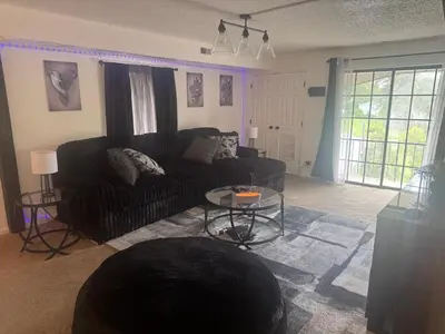 a living room with a black couch and a table at Elegance Escape