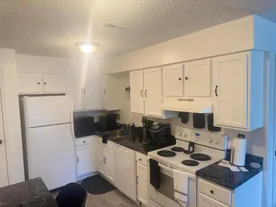 a kitchen with white cabinets and a white refrigerator at Elegance Escape