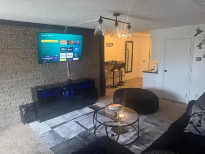 a living room with a fireplace and a tv on a brick wall at Elegance Escape