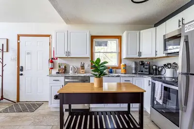 a kitchen with white cabinets and a table with a plant at Blue Diamond Hot Tub Fire Pit 3 BDR in Tobyhanna