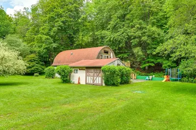 a barn with a red roof in a green field at Hike and Fish Delaware River Cabin with Views in East Branch