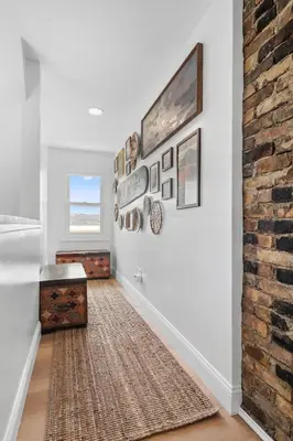 a hallway with white walls and a brick wall at Hudson Escape W Hot Tub Bridge View in Highland