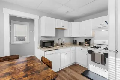 a kitchen with white cabinets and a wooden table at Sunny Room Steps from SCSU in New Haven