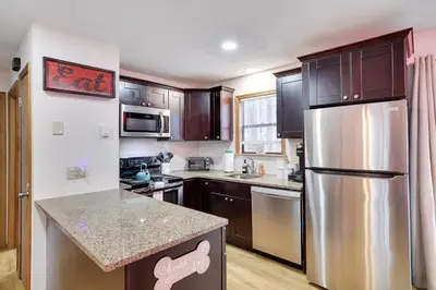 a kitchen with a stainless steel refrigerator and wooden cabinets at Hot tub - Game Loft & Arcade - 2 King Beds - Pet Friendly in Tobyhanna
