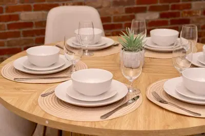 a wooden table with white plates and wine glasses at Modern 3BR Near EWR, Parking, 25 Min NYC in Kearny
