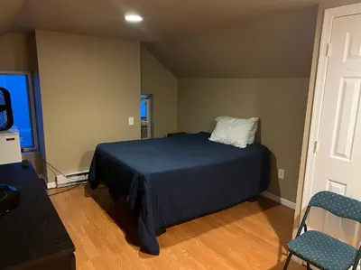 a bedroom with a bed and a chair and a window at Near East Stroudsburg University in East Stroudsburg