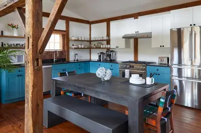 a kitchen with blue cabinets and a wooden table at The Kent Collection - The Garden Cottages in Kent