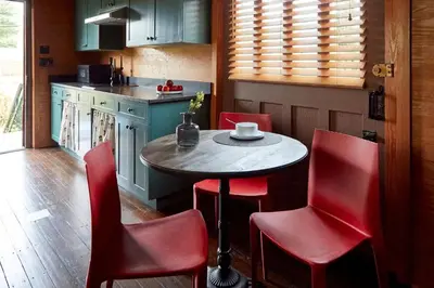 a small kitchen with a table and red chairs at The Kent Collection - The Garden Cottages in Kent