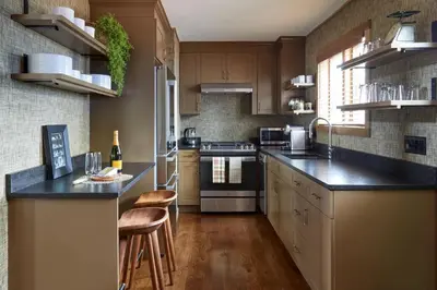 a kitchen with wooden cabinets and black counter tops at The Kent Collection - The Garden Cottages in Kent