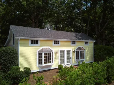 a yellow house with white windows in a yard at The Kent Collection - The Garden Cottages in Kent