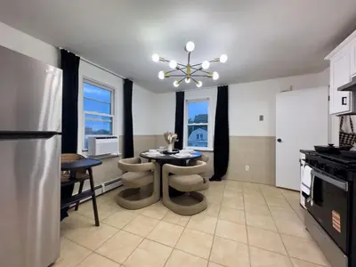 a kitchen with a table and a refrigerator at Elegant NYC View Stay Park Free 6 beds Sleep 8 in Kearny